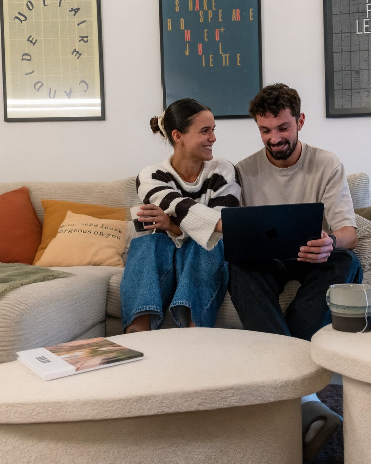 Le même couple, côte à côte sur le canapé, sourit devant l'app ouverte sur l'ordinateur